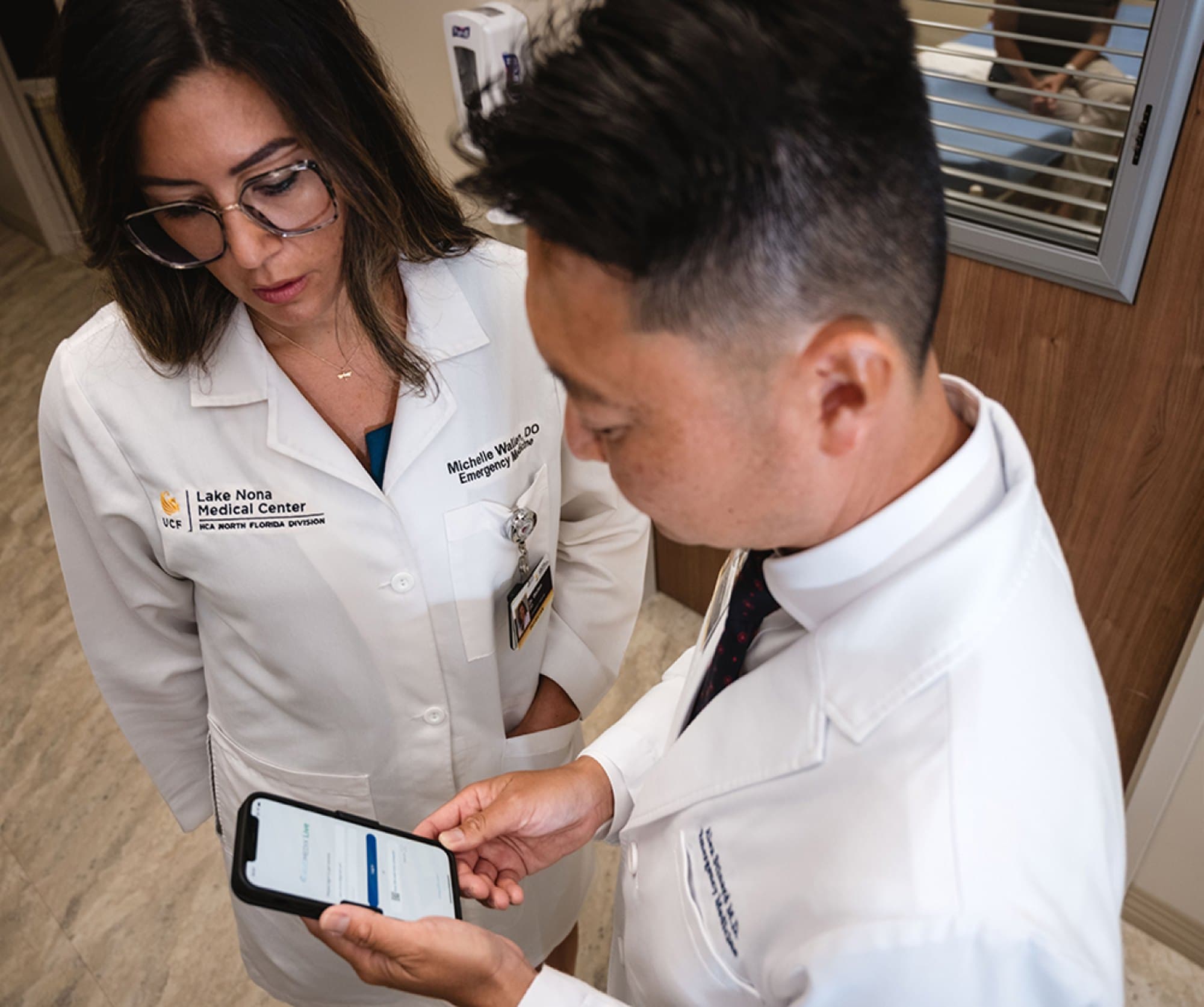 Two HCA emergency medicine clinicians at Lake Nona Medical Center reviewing an AI-drafted note on Augmedix Go ED